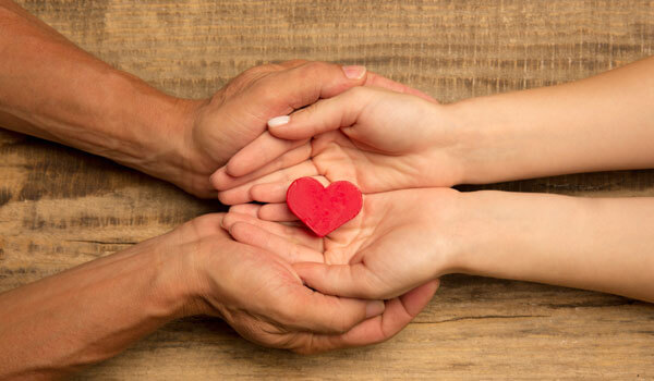 Human Hands Holding, Giving Heart Isolated On Wooden Background